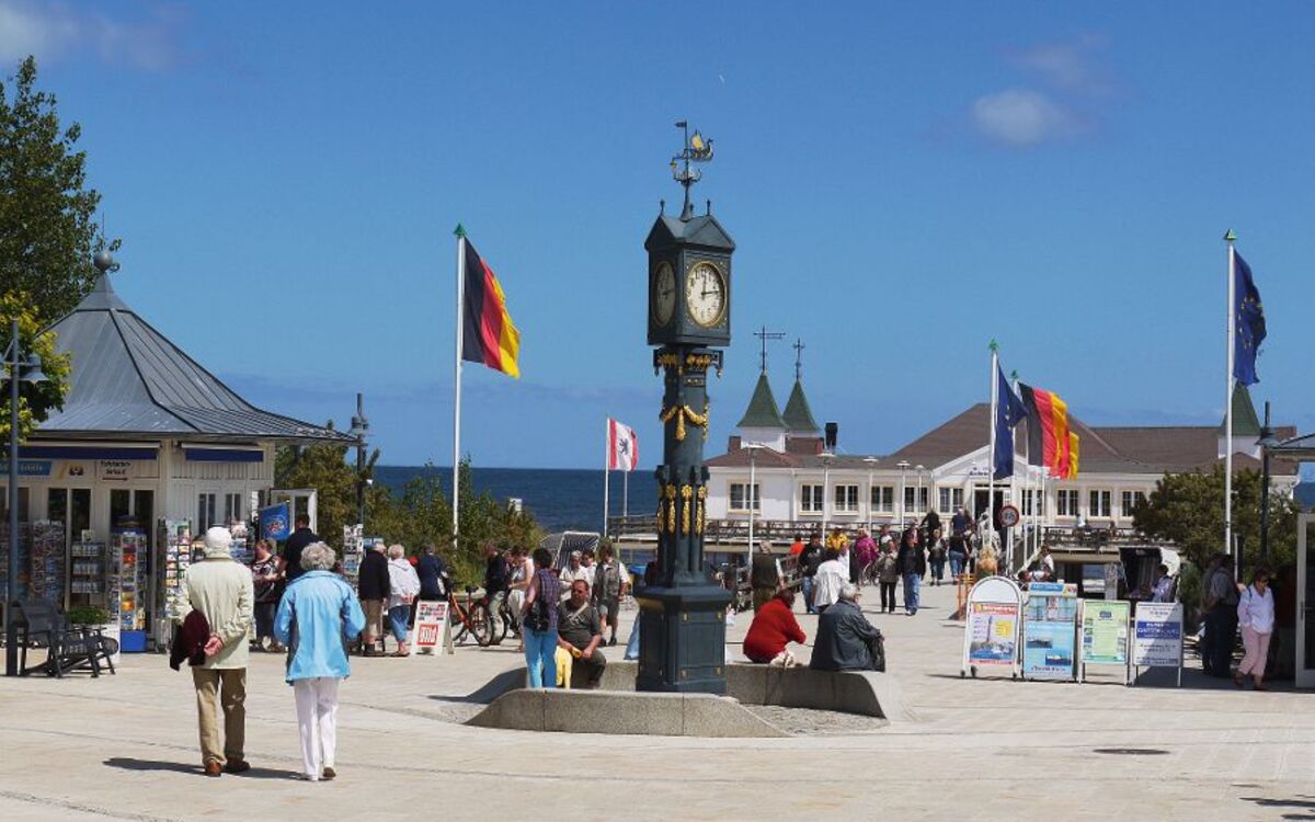 Menschen flanieren auf der Seebrücke in Ahlbeck, Deutschland, bei sonnigem Wetter.