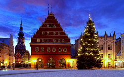 Historischer Marktplatz im Winter mit Weihnachtsbaum und beleuchtetem Gebäude. Greifswald