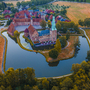 Luftaufnahme einer mittelalterlichen Burg mit Wassergraben und umliegender Landschaft.