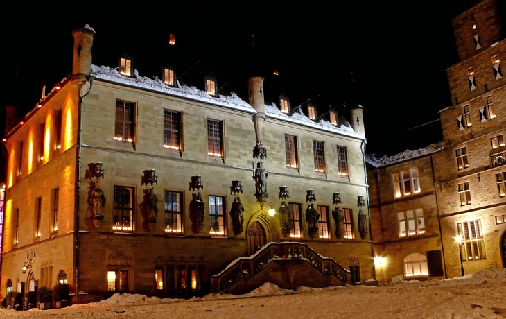 Historisches Gebäude bei Nacht, beleuchtet und von Schnee umgeben.