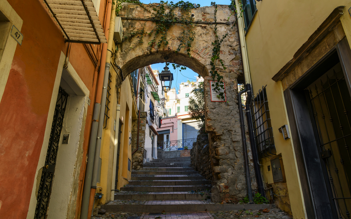 Treppenstraße mit steinernem Bogen und überwachsenen Pflanzen in einer Altstadt. Sanremo