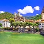 Dolceaqua Mittelalterliche Stadt mit Fluss und Hügeln im Hintergrund bei sonnigem Wetter.