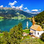 Kirche und halbversunkener Kirchturm an einem See in den Alpen.