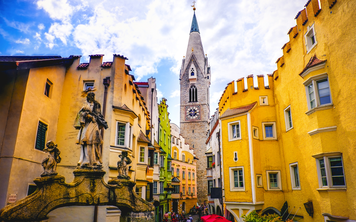 Häuserfassaden und Kirchturm an einem sonnigen Platz in Italien.