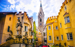 Häuserfassaden und Kirchturm an einem sonnigen Platz in Italien.
