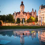Altes Rathaus in Leipzig bei Abenddämmerung mit Spiegelung im Wasser im Vordergrund.