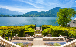 Terrasse mit Blick auf einen See und umliegende Berge bei klarem Himmel Vill Carlotta