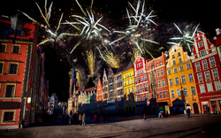 Feuerwerk über einem bunten, historischen Stadtplatz bei Nacht.