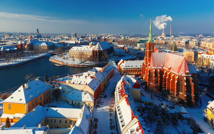 Winterliche Stadtansicht mit historischen Gebäuden und einer Kirche im Vordergrund.