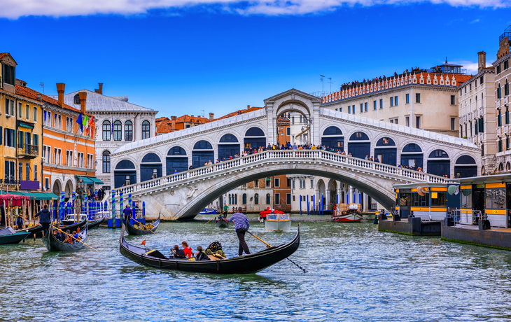 Rialtobrücke und Canal Grande in Venedig mit einer vorbeifahrenden Gondel.