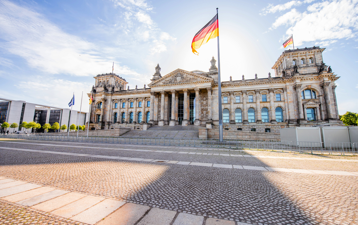 Das Reichstagsgebäude in Berlin mit wehender deutscher Flagge.