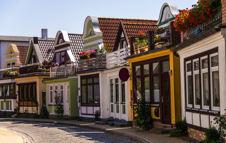 Reihe bunter, traditioneller Häuser mit Blumen in der Sonne.
