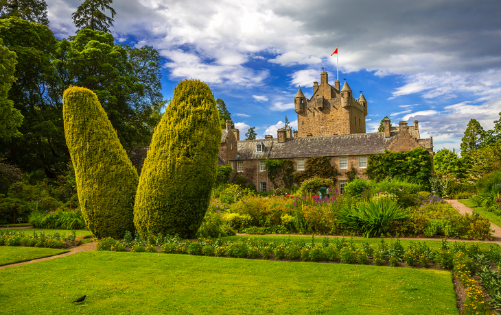 Cawdor Castle in Schottland mit gepflegtem Garten und Zierbrunnen an einem Sommertag.