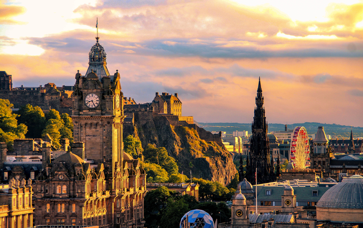 Stadtansicht von Edinburgh bei Sonnenuntergang mit historischen Gebäuden und Burg.