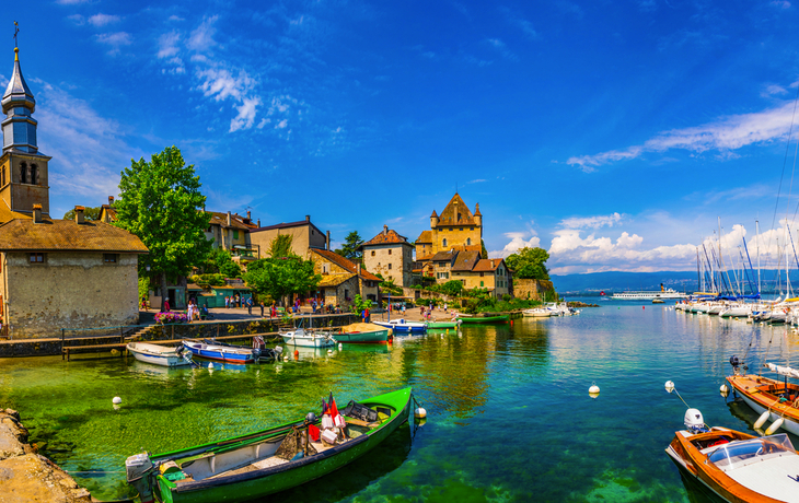 Blick auf eine malerische Hafenstadt mit Booten und historischen Gebäuden am Wasser.