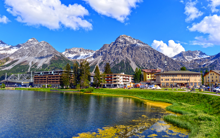 Berglandschaft mit See, Gebäuden und blauem Himmel