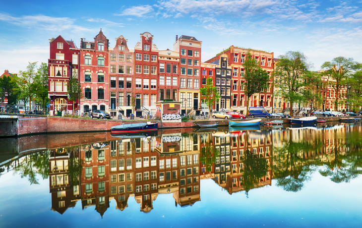 Reihe von Backsteinhäusern spiegelt sich im Wasser eines Kanals.