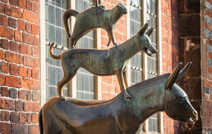 Bronzestatue der Bremer Stadtmusikanten vor Backsteingebäude