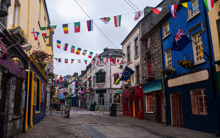 Bunte Häuserfassaden und Wimpelketten in einer europäischen Gasse.