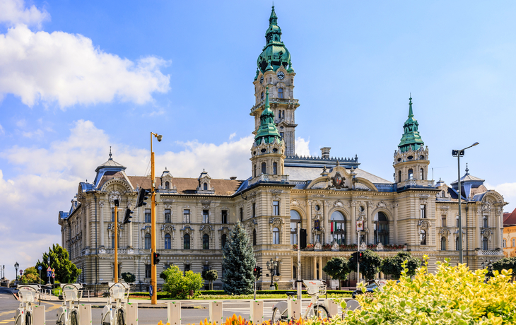 Historisches Gebäude mit Türmen und blauer Kuppel an einem sonnigen Tag.