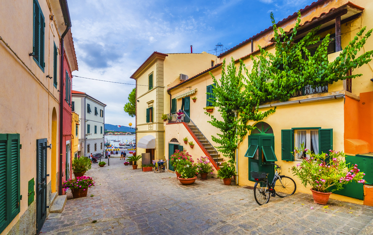 Malerische italienische Gasse mit bunten Gebäuden, Blumen und einem Fahrrad.