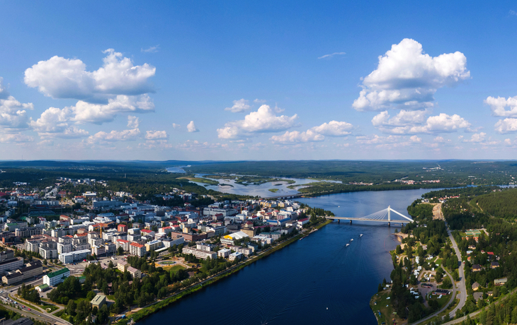 Stadtansicht mit Fluss und Brücke aus der Luft am Tag unter blauem Himmel.