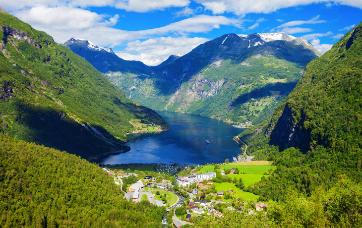 Fjordlandschaft mit Bergen und Wasser, grüne Täler und blauer Himmel im Hintergrund