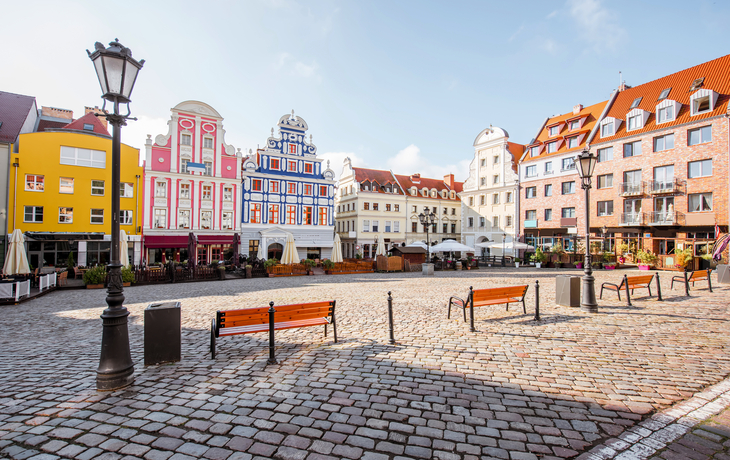 Historischer Marktplatz mit bunten Giebelhäusern und Kopfsteinpflaster.