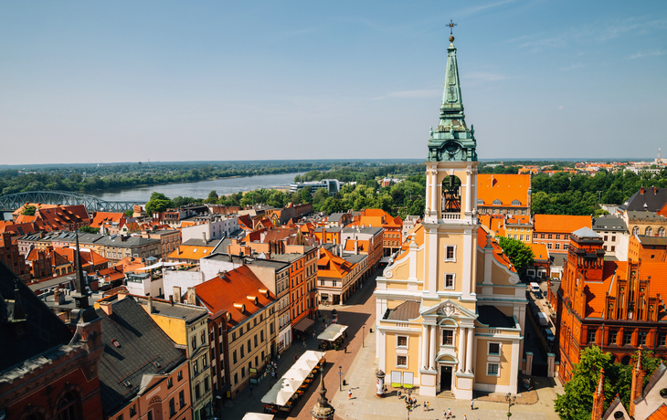 Stadtansicht von Toruń mit Kirche und Fluss im Hintergrund.