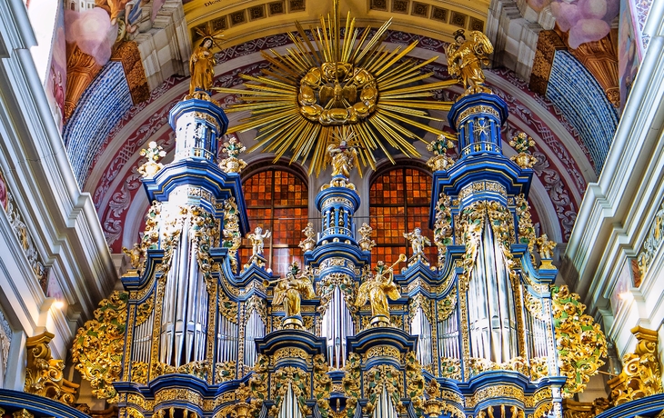 Prächtige Orgel mit verziertem Prospekt in farbenreicher Barockkirche.