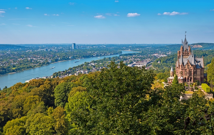 Schloss Drachenburg vor Rheinlandschaft und Himmel.