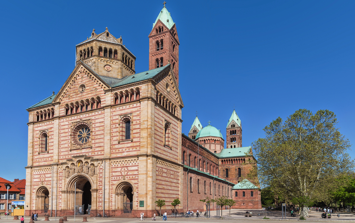 Romanische Kathedrale mit markantem Turm und blauem Himmel im Hintergrund.