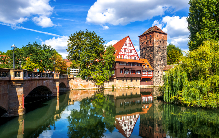 Fachwerkhaus und Turm am Fluss in Nürnberg unter blauem Himmel