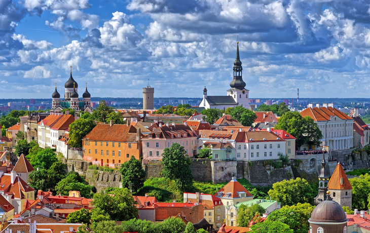 Historische Altstadt mit Kirchen und bunten Dächern unter wolkigem Himmel.