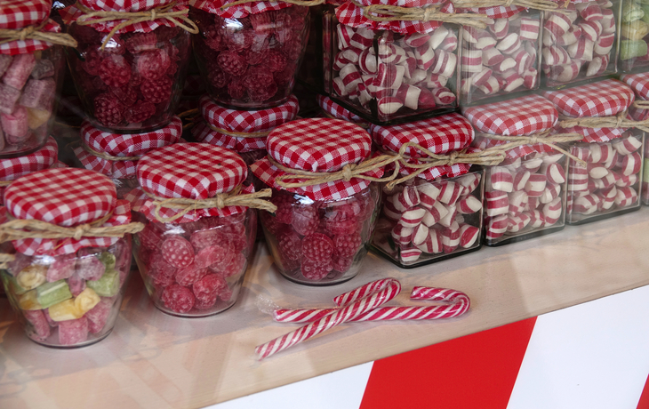 Verschiedene Süßigkeiten in Gläsern mit karierter Abdeckung in einem Schaufenster