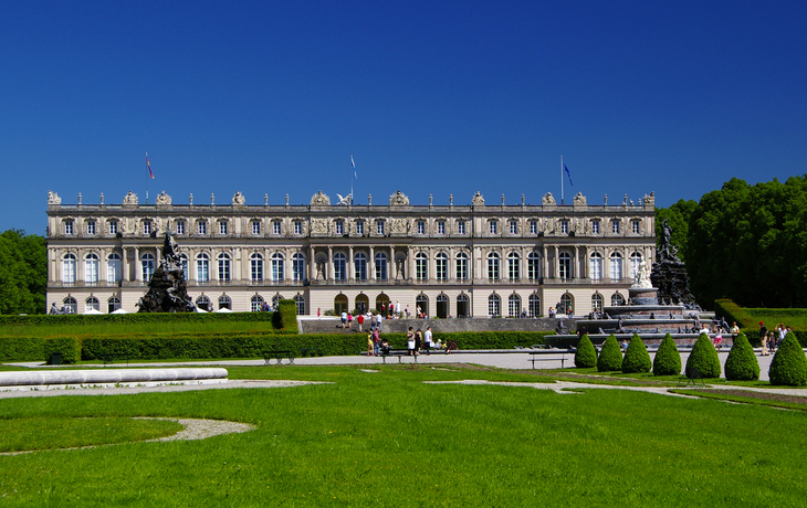 Historisches Schloss mit gepflegtem Garten und blauen Himmel.