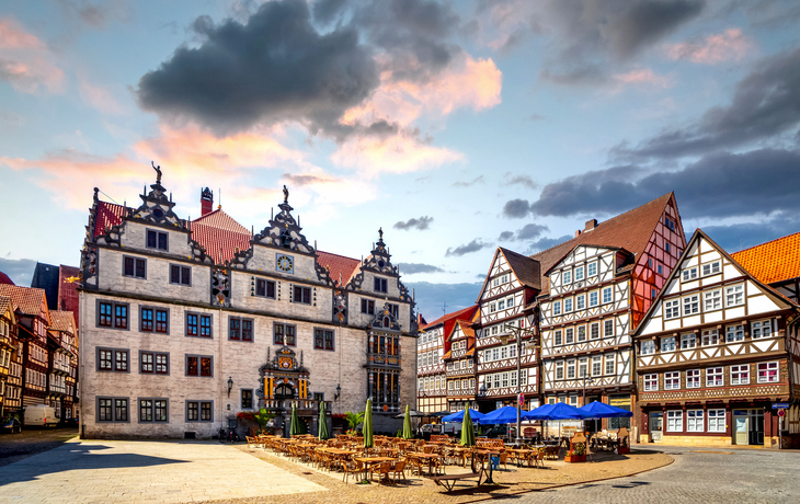 Historischer Marktplatz mit Fachwerkhäusern und leeren Cafétischen bei Sonnenuntergang