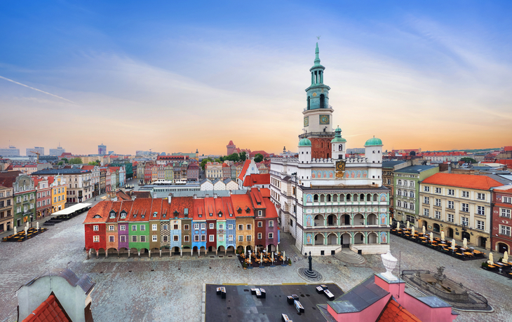 Stadtplatz mit historischen Gebäuden und einem Turm bei Sonnenuntergang.