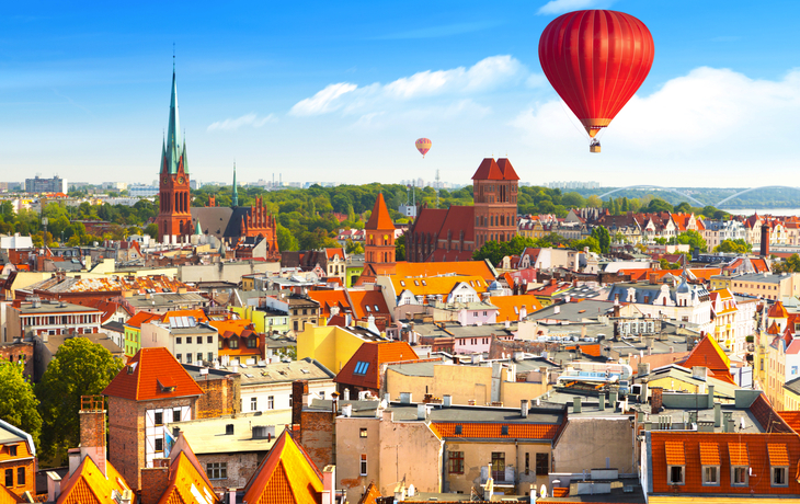 Heißluftballons über einer europäischen Stadt mit historischen Gebäuden.