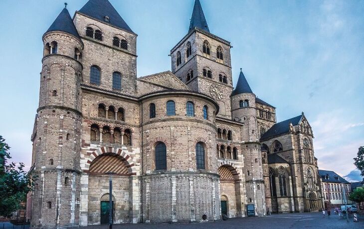 Romanische Kirche mit mehreren Türmen bei Tageslicht.