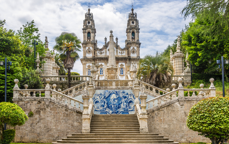 Historisches Gebäude mit verzierten Treppen und grüner Umgebung.