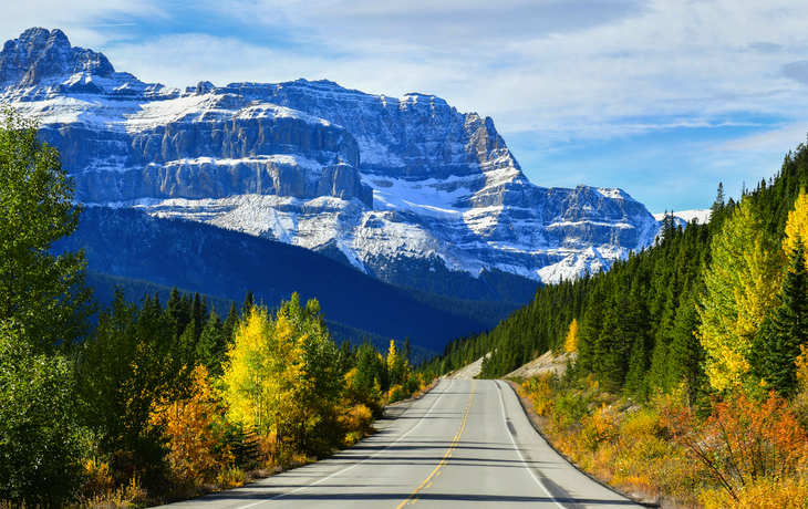 Gebirgsstraße im Herbst mit schneebedeckten Bergen im Hintergrund