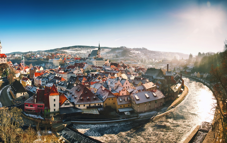 Panoramablick auf eine historische Stadt mit Fluss und schneebedeckten Dächern im Winter.
