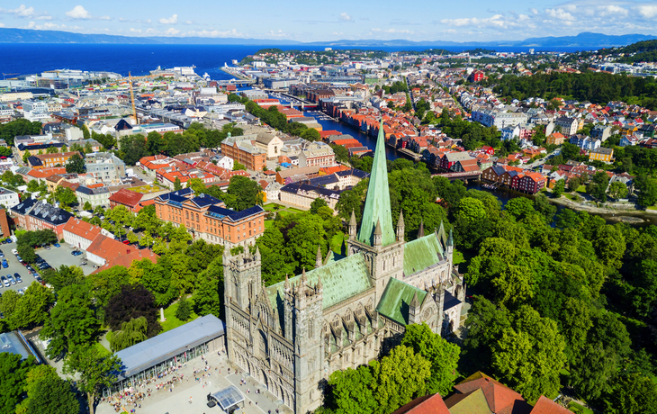 Luftaufnahme einer Stadt mit einer großen Kathedrale und umliegender grüner Landschaft.