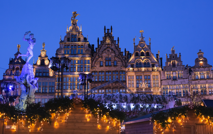 Historische Gebäude und Weihnachtsmarktlichter in Antwerpen bei Nacht.