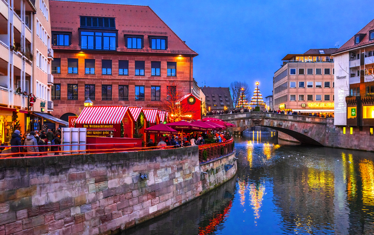 Weihnachtsmarkt am Kanal mit Brücke in der Dämmerung