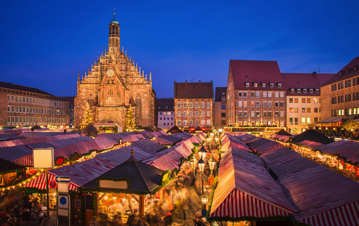 Weihnachtsmarkt mit Kirche bei Abenddämmerung in Nürnberg