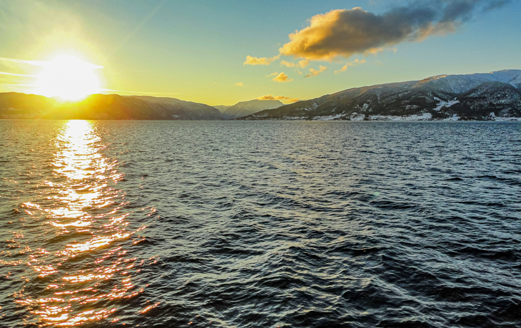 Sonnenuntergang über einem ruhigen See mit schneebedeckten Bergen im Hintergrund