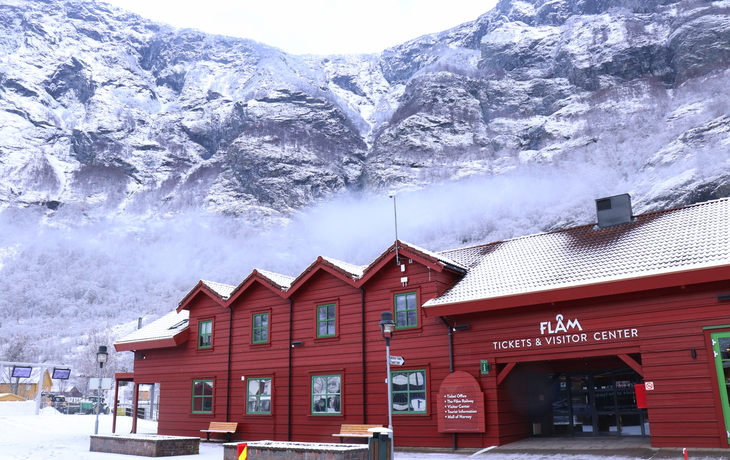 Rotes Besucherzentrum in schneebedeckter Berglandschaft.