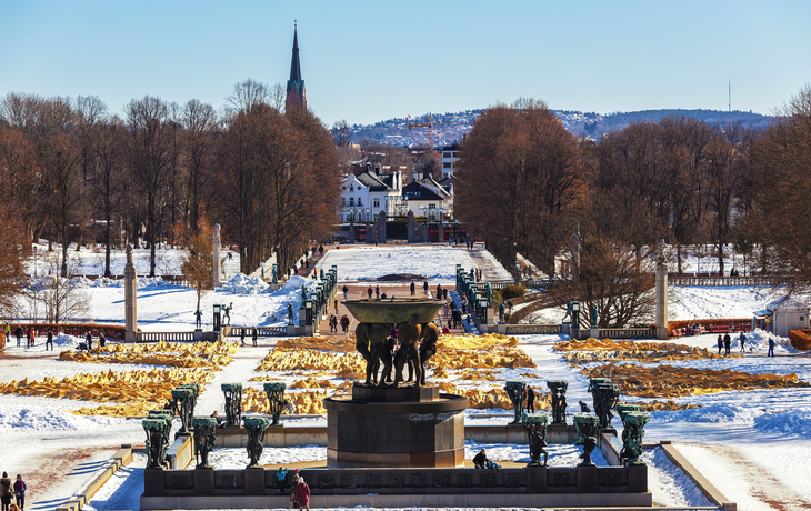 Parklandschaft im Winter mit Skulpturen und schneebedeckten Wegen.
